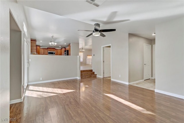 unfurnished living room featuring recessed lighting, ceiling fan with notable chandelier, visible vents, baseboards, and light wood-type flooring