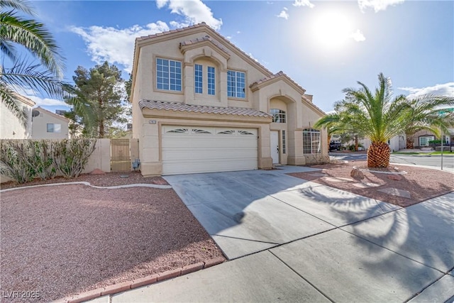 mediterranean / spanish house with a tile roof, driveway, fence, and stucco siding