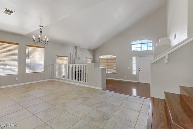 entrance foyer with baseboards, visible vents, tile patterned floors, an inviting chandelier, and high vaulted ceiling