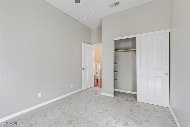 unfurnished bedroom with attic access, baseboards, visible vents, carpet flooring, and a closet