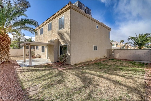 back of house with a lawn, a patio area, a fenced backyard, and stucco siding