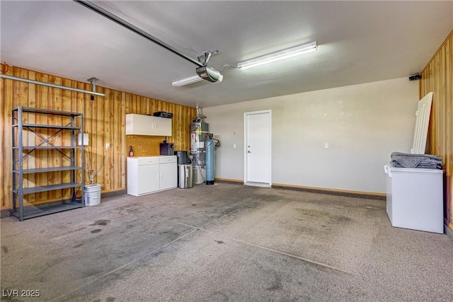 garage with a garage door opener, strapped water heater, wood walls, and baseboards