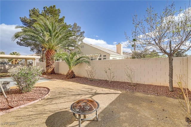 view of yard featuring a fire pit, a patio area, and a fenced backyard