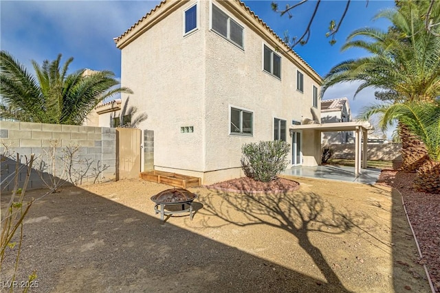 rear view of house featuring a fire pit, a patio, a tiled roof, fence, and stucco siding