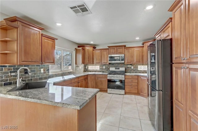 kitchen with light tile patterned floors, stainless steel appliances, a peninsula, a sink, and visible vents