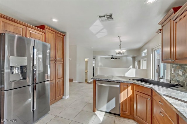 kitchen featuring stainless steel appliances, visible vents, backsplash, a sink, and a peninsula