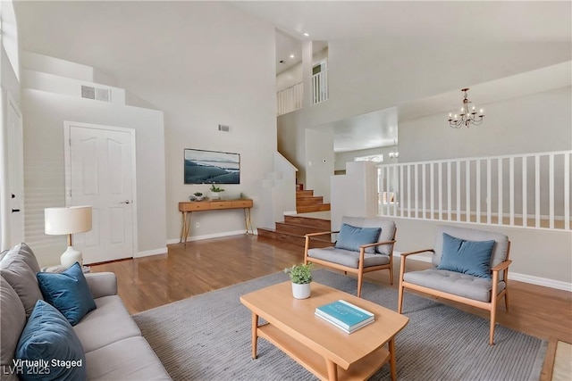 living room with stairway, wood finished floors, visible vents, and a notable chandelier