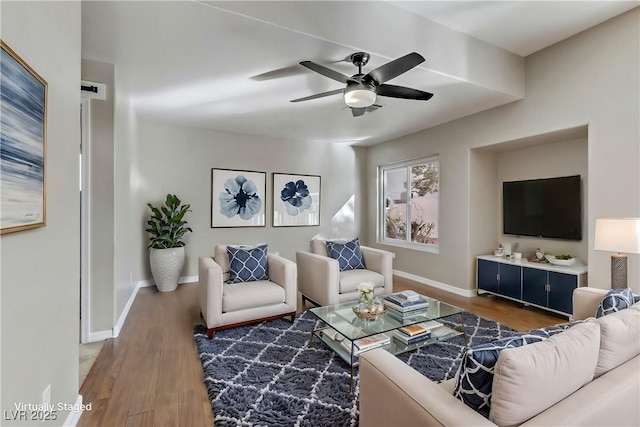 living room with ceiling fan, baseboards, and wood finished floors