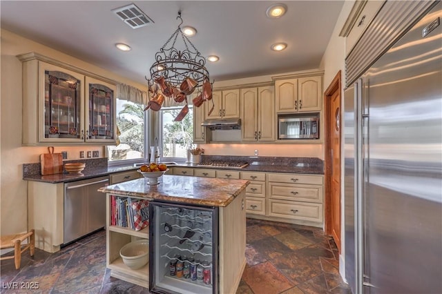 kitchen with cream cabinetry, visible vents, stone finish floor, and built in appliances