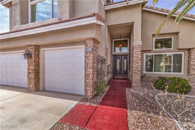 view of exterior entry featuring stone siding, driveway, an attached garage, and stucco siding