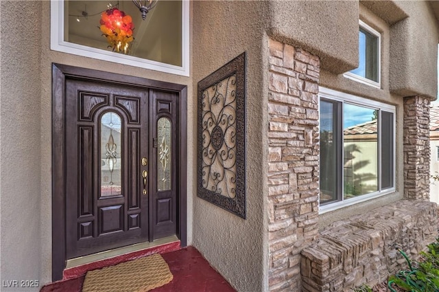 entrance to property featuring stone siding and stucco siding