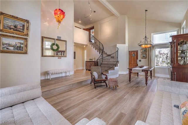 foyer featuring stairs, high vaulted ceiling, wood finished floors, and baseboards