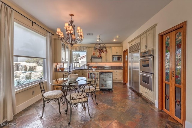 dining space featuring visible vents, baseboards, wine cooler, stone finish flooring, and a notable chandelier