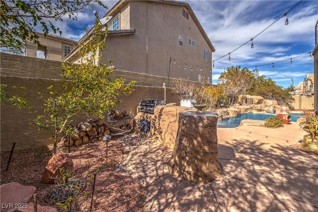 view of property exterior with stucco siding, a fenced backyard, an outdoor kitchen, and a patio