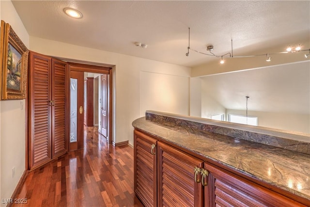 interior space with vaulted ceiling, dark wood finished floors, a textured ceiling, and baseboards