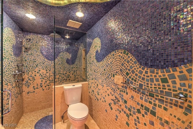 bathroom with tile patterned flooring, a shower stall, toilet, and tile walls