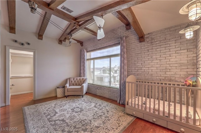 unfurnished bedroom with brick wall, wood finished floors, visible vents, and baseboards