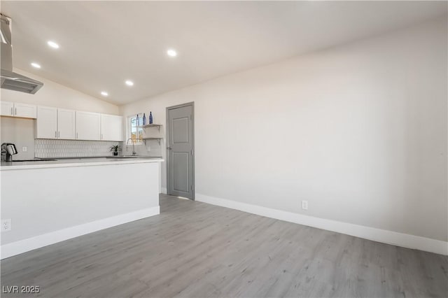 kitchen featuring light countertops, light wood finished floors, backsplash, and white cabinetry