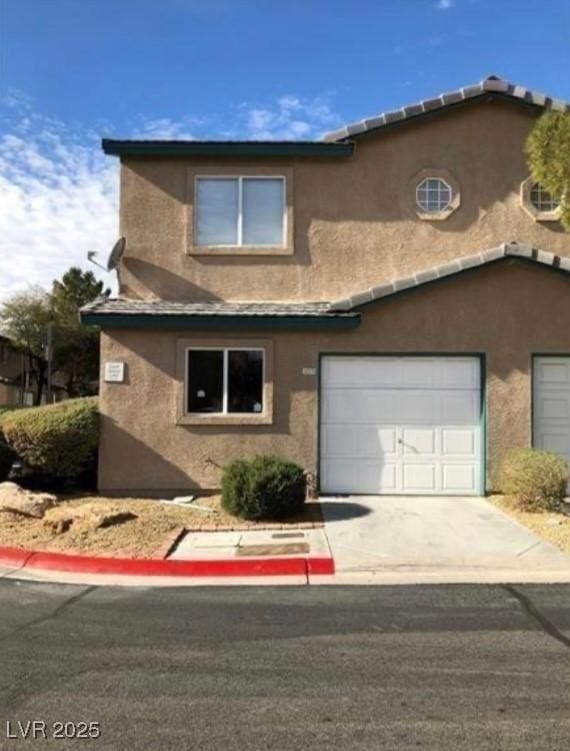 view of front of house with concrete driveway, an attached garage, and stucco siding