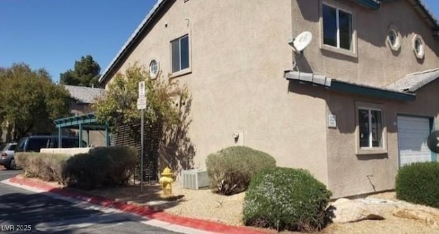 view of side of home with central AC unit and stucco siding