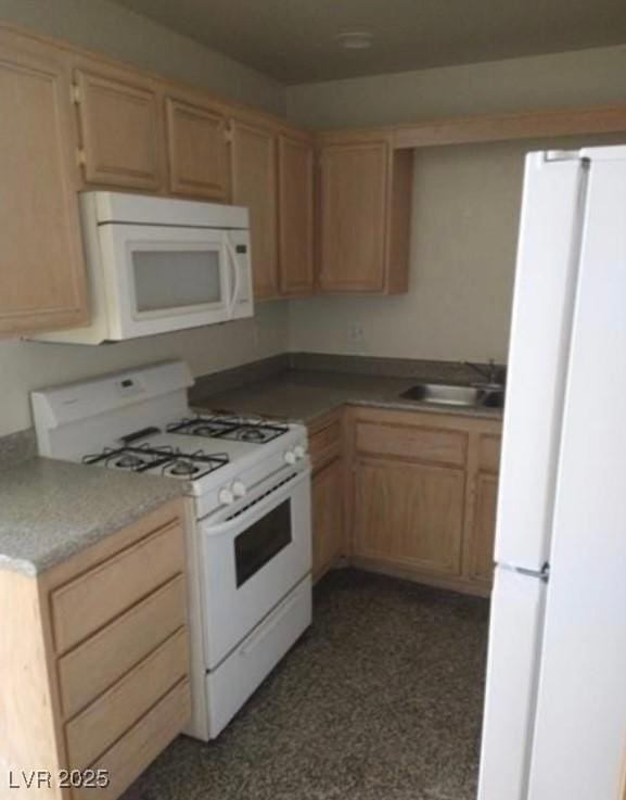 kitchen featuring white appliances, light brown cabinets, and a sink