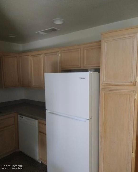 kitchen with dark countertops, white appliances, and visible vents