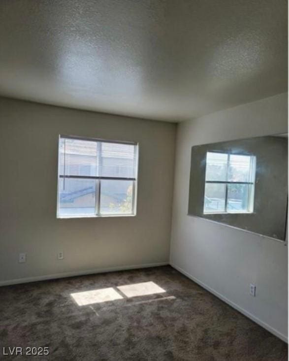 carpeted empty room featuring a textured ceiling and baseboards