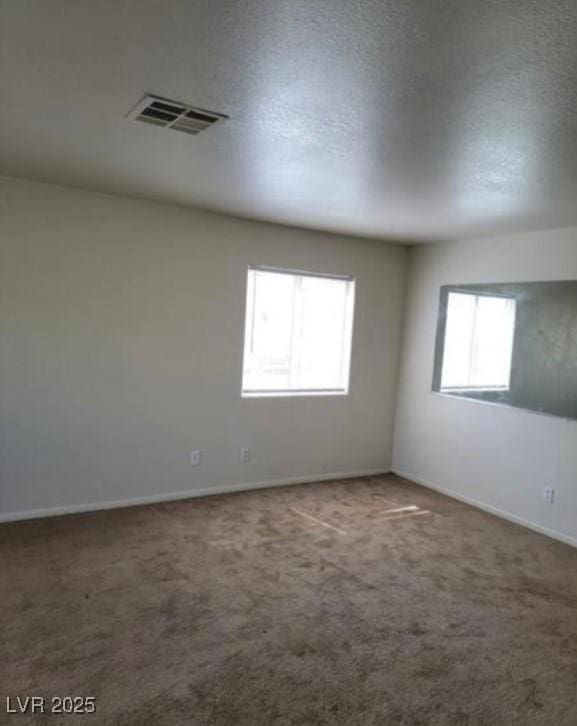 unfurnished room featuring a textured ceiling, carpet flooring, visible vents, and baseboards