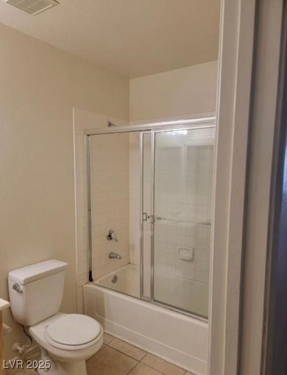 bathroom with tile patterned flooring, visible vents, toilet, and combined bath / shower with glass door