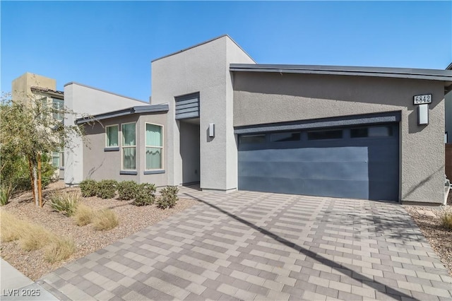 view of front of property with a garage, decorative driveway, and stucco siding