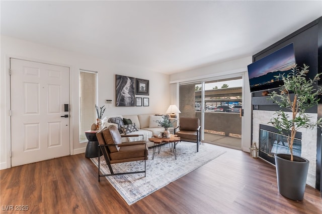 living room with dark wood-type flooring and a glass covered fireplace