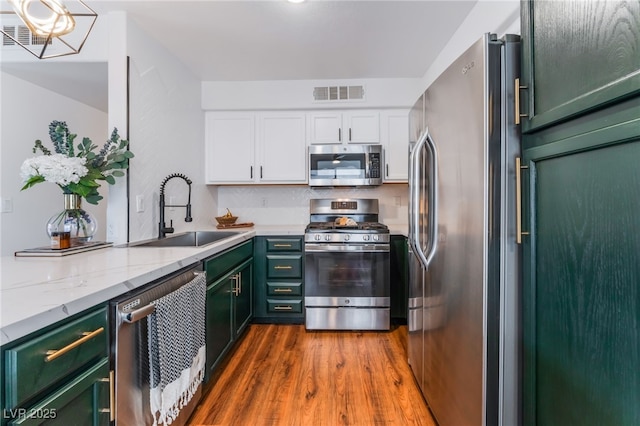 kitchen featuring green cabinets, stainless steel appliances, a sink, and visible vents