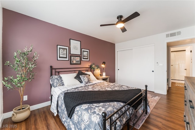 bedroom with ceiling fan, wood finished floors, visible vents, baseboards, and a closet