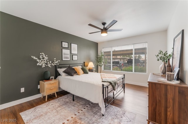 bedroom featuring ceiling fan, baseboards, and wood finished floors