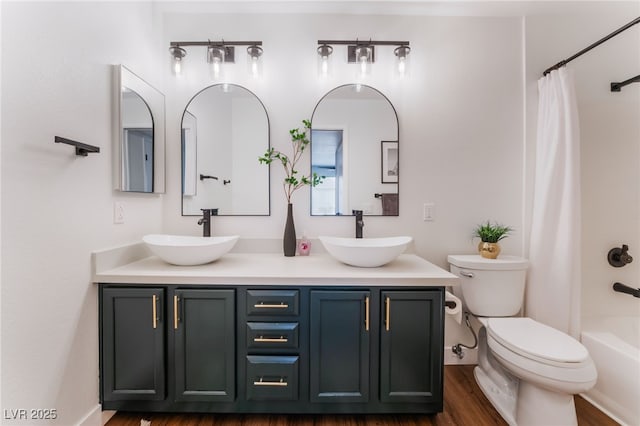 bathroom featuring wood finished floors, a sink, toilet, and double vanity