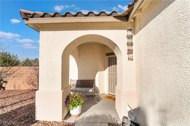 entrance to property with a tile roof and stucco siding