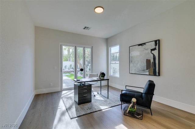 office space featuring wood finished floors, visible vents, and baseboards