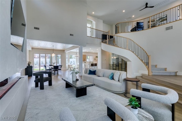 living room with a high ceiling, stairs, visible vents, and recessed lighting