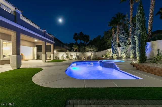 pool at night with a patio area, a fenced backyard, and a pool with connected hot tub