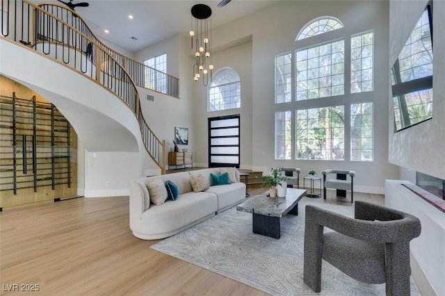 living room with baseboards, stairway, wood finished floors, a notable chandelier, and recessed lighting