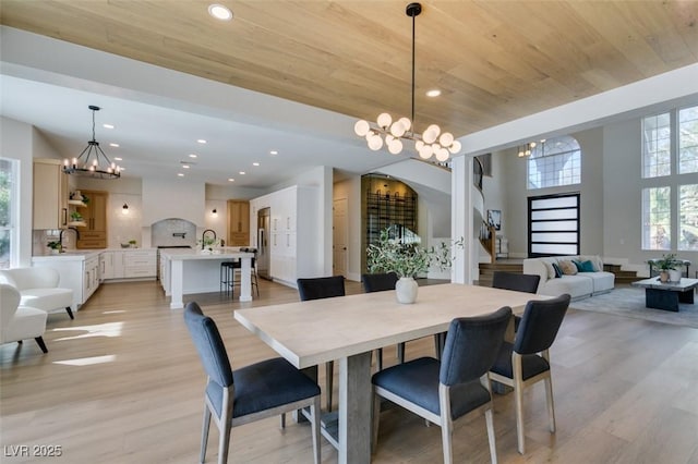 dining room with wood ceiling, a chandelier, arched walkways, and light wood-style flooring