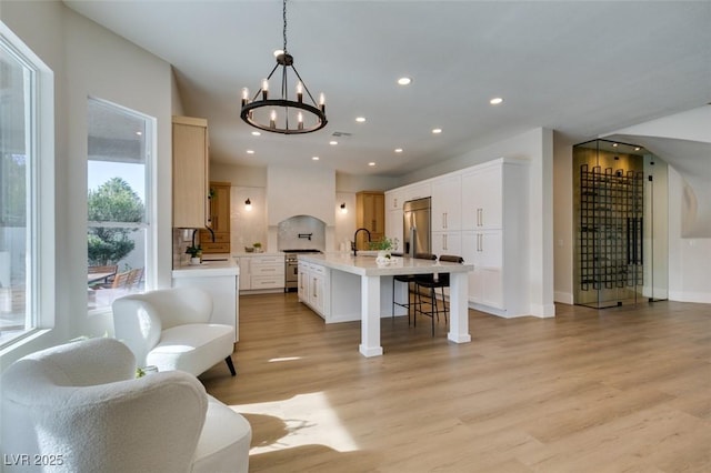 kitchen featuring stainless steel appliances, light countertops, light wood-style floors, a kitchen bar, and a sink