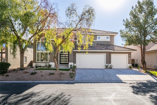 view of front facade featuring driveway, a tiled roof, an attached garage, and stucco siding