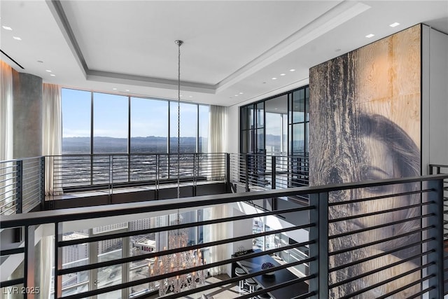 stairway with a tray ceiling and a wall of windows