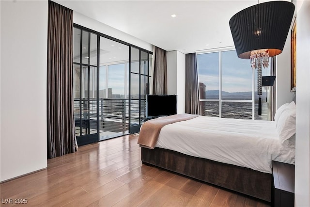 bedroom featuring access to outside, expansive windows, wood finished floors, and multiple windows