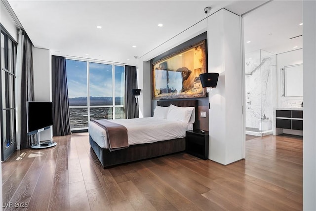 bedroom featuring expansive windows, recessed lighting, wood finished floors, and ensuite bathroom