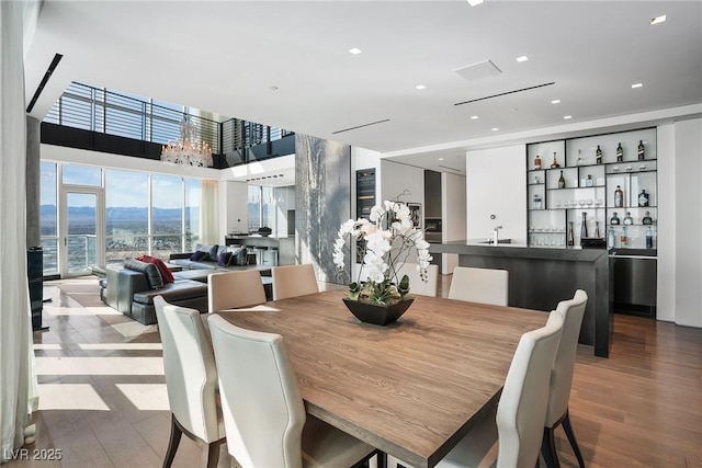 dining room with wet bar, wood finished floors, and an inviting chandelier