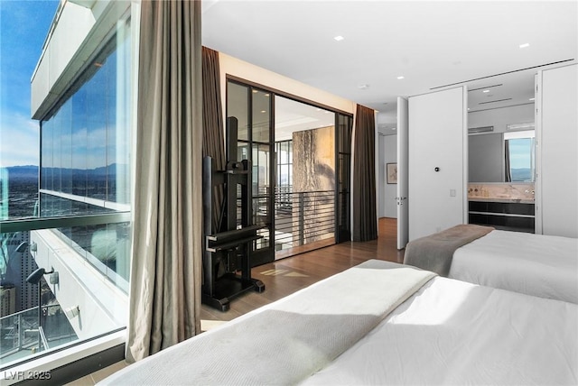 bedroom featuring multiple windows, ensuite bathroom, and wood finished floors