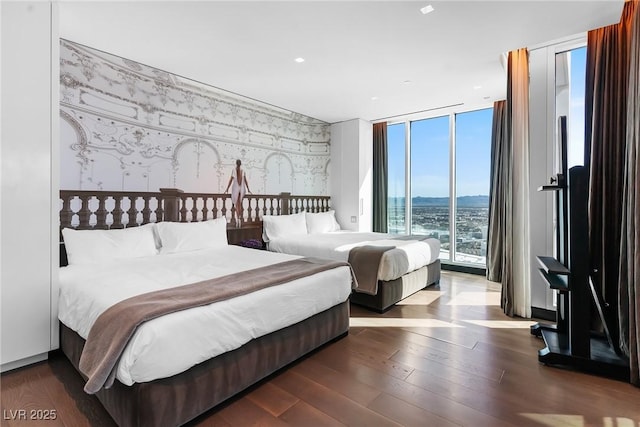 bedroom featuring dark wood-style floors, wallpapered walls, and floor to ceiling windows