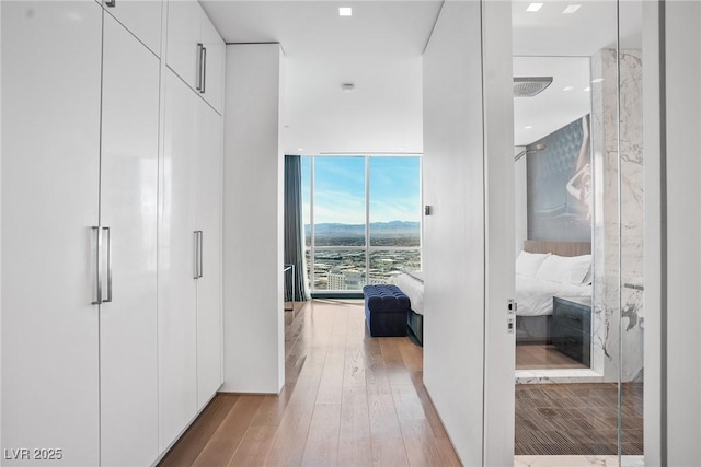 hall with floor to ceiling windows and wood finished floors